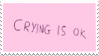 A pink stamp with written text that reads in all capital letters, 'Crying is OK'