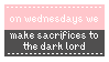 A pink and black stamp with a lacy white border and white text. The text reads, 'On Wednesdays, we make sacrifices to the dark lord.' The text is a corrupted version of a quote from the movie 'Mean Girls'